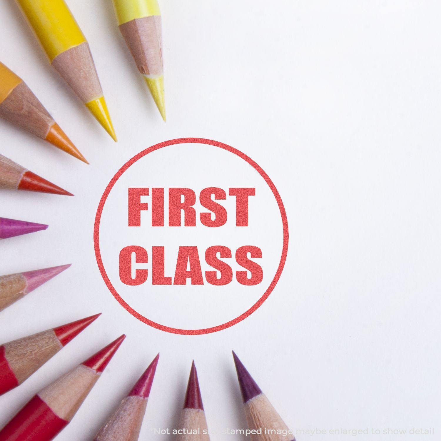 Round First Class Xstamper Stamp imprint in red on white paper, surrounded by colored pencils arranged in a circular pattern.