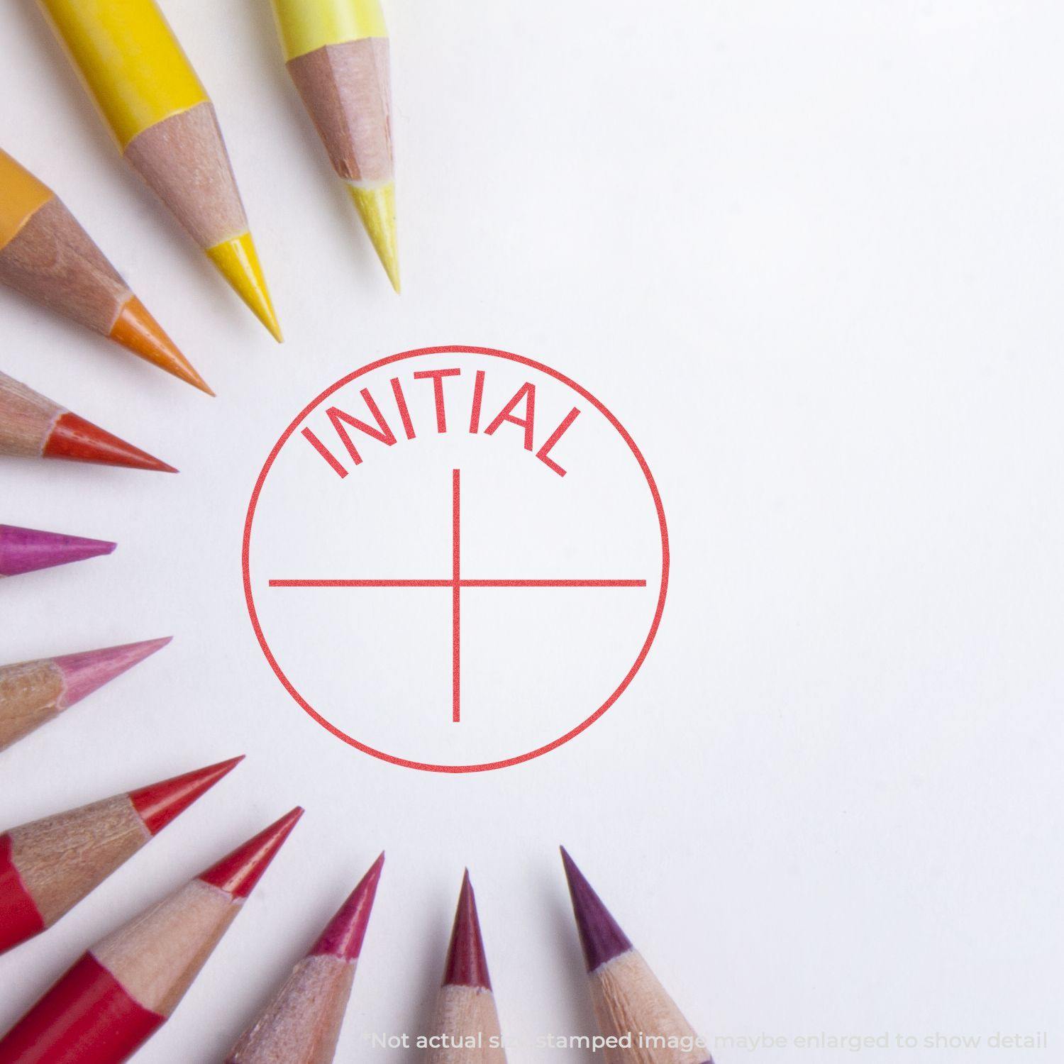 Round Initial Xstamper Stamp imprint in red on white paper, surrounded by colorful pencils arranged in a circular pattern.