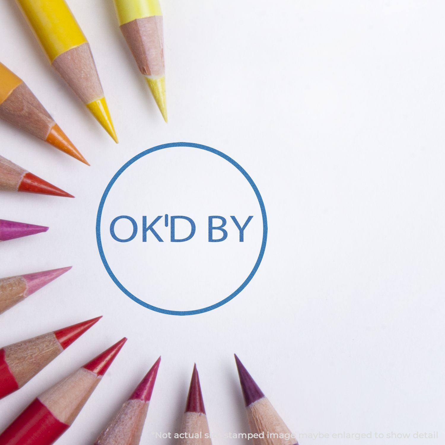 Round OK'D By Xstamper Stamp impression on white paper, surrounded by colorful pencils arranged in a circle.