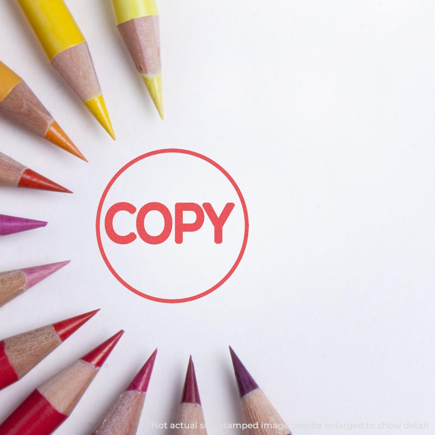 Round Red Copy Xstamper Stamp imprint on white paper, surrounded by colored pencils arranged in a circular pattern.