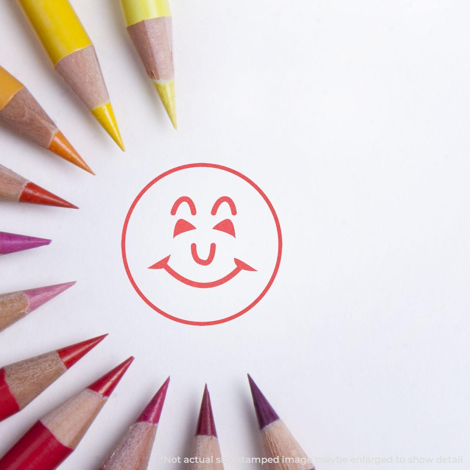 Round Smiley Face Xstamper Stamp in red ink on white paper, surrounded by colored pencils arranged in a semi-circle.