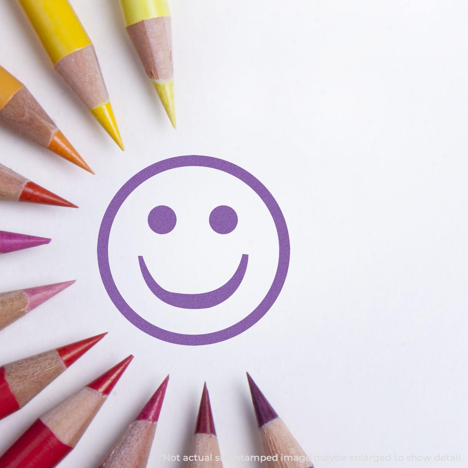 Round Violet Smiley Face Xstamper Stamp impression surrounded by colorful pencils on white paper.