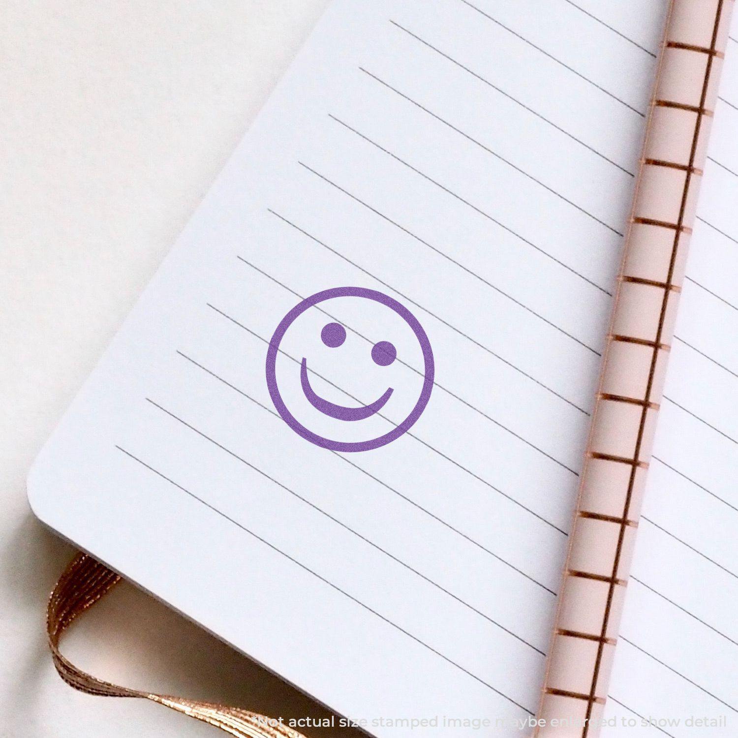 Round Violet Smiley Face Xstamper Stamp imprint on a lined notebook page with a copper spiral binding.