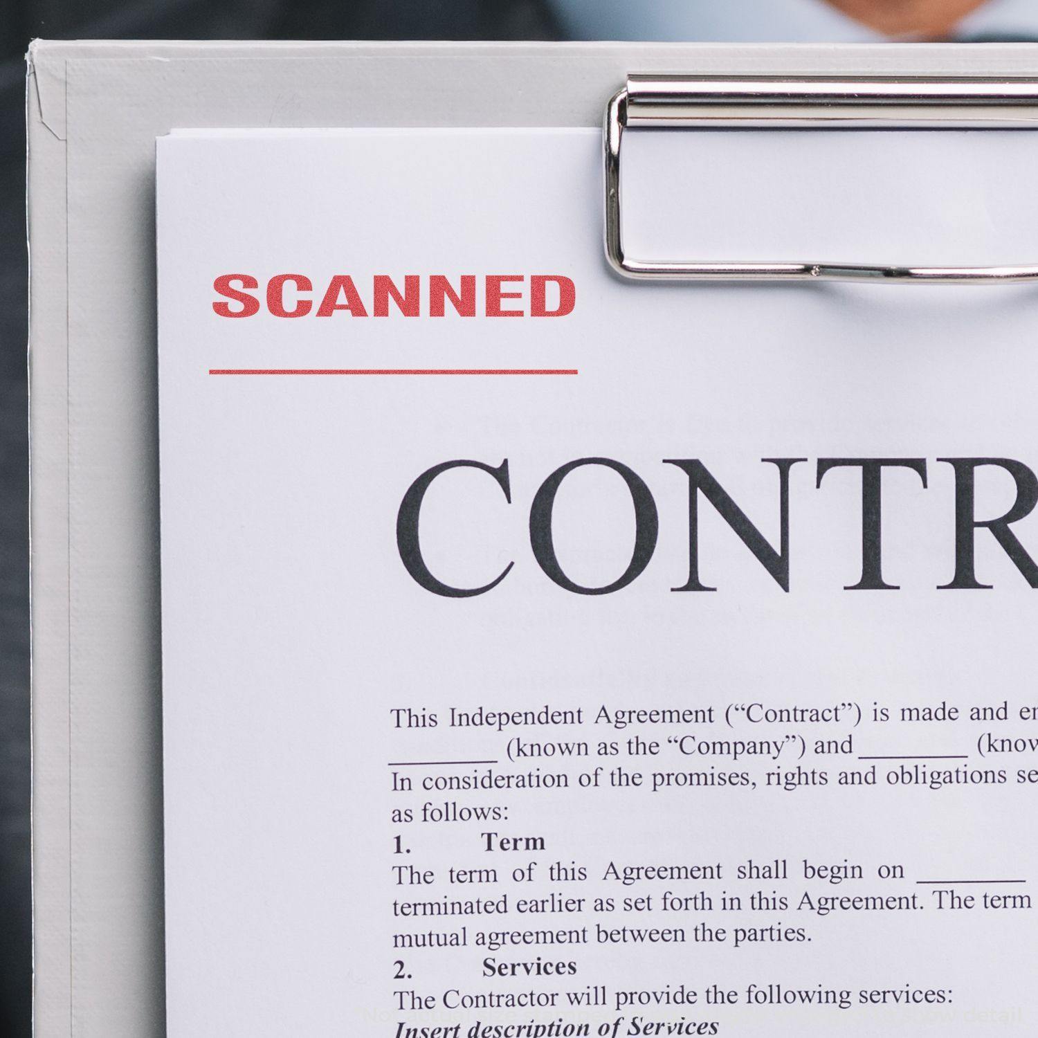 A clipboard holds a contract stamped with "SCANNED" in red ink using a Scanned Xstamper Stamp.