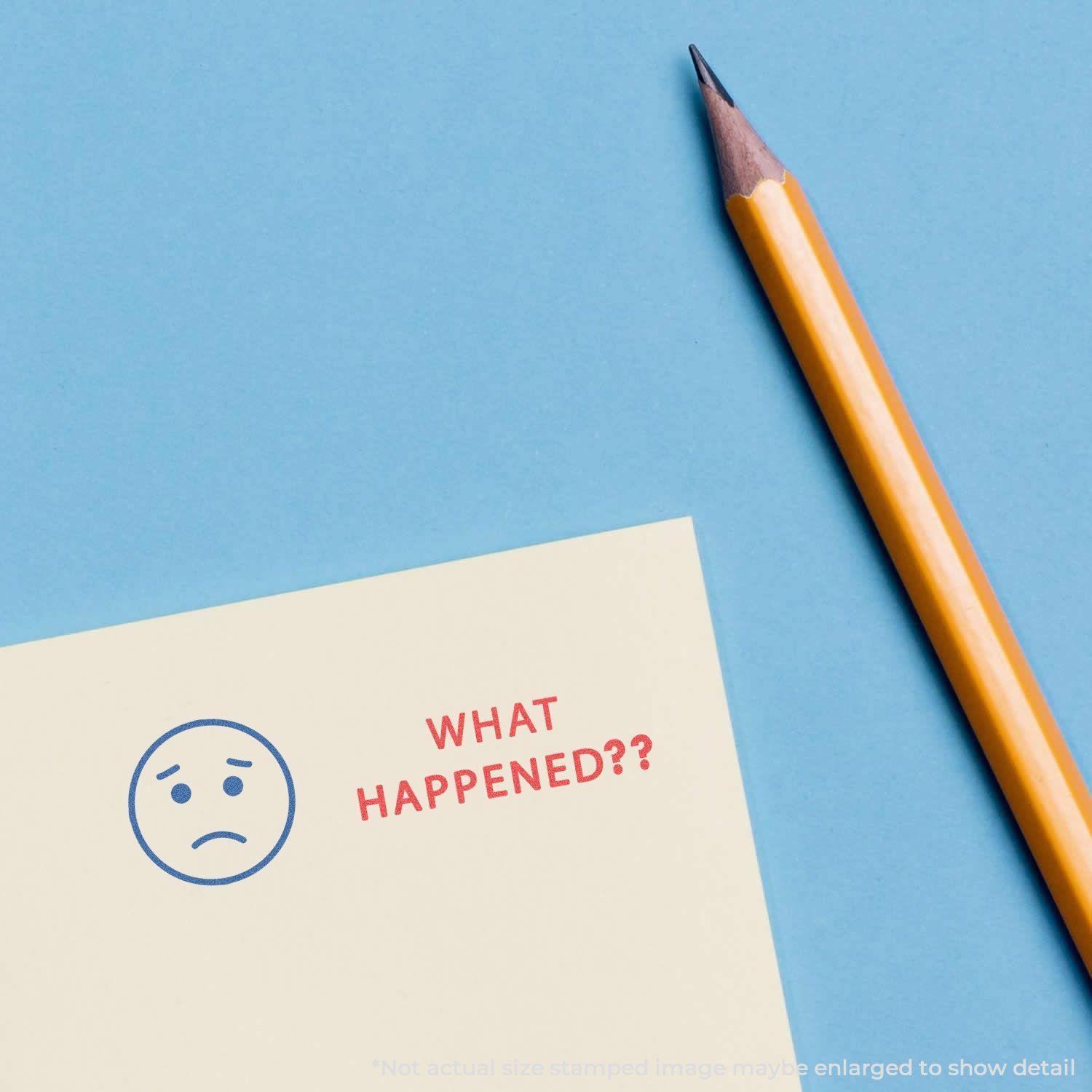 Two-Color What Happened? Xstamper Stamp impression on paper with a sad face and text WHAT HAPPENED?? next to a yellow pencil on a blue background.