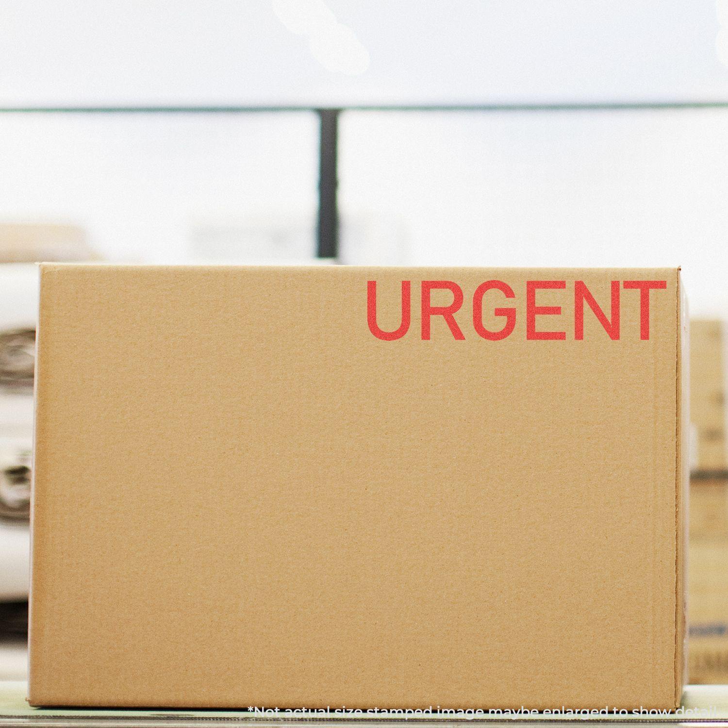 A cardboard box stamped with URGENT in red using the Urgent Xstamper Stamp, placed in a warehouse setting.